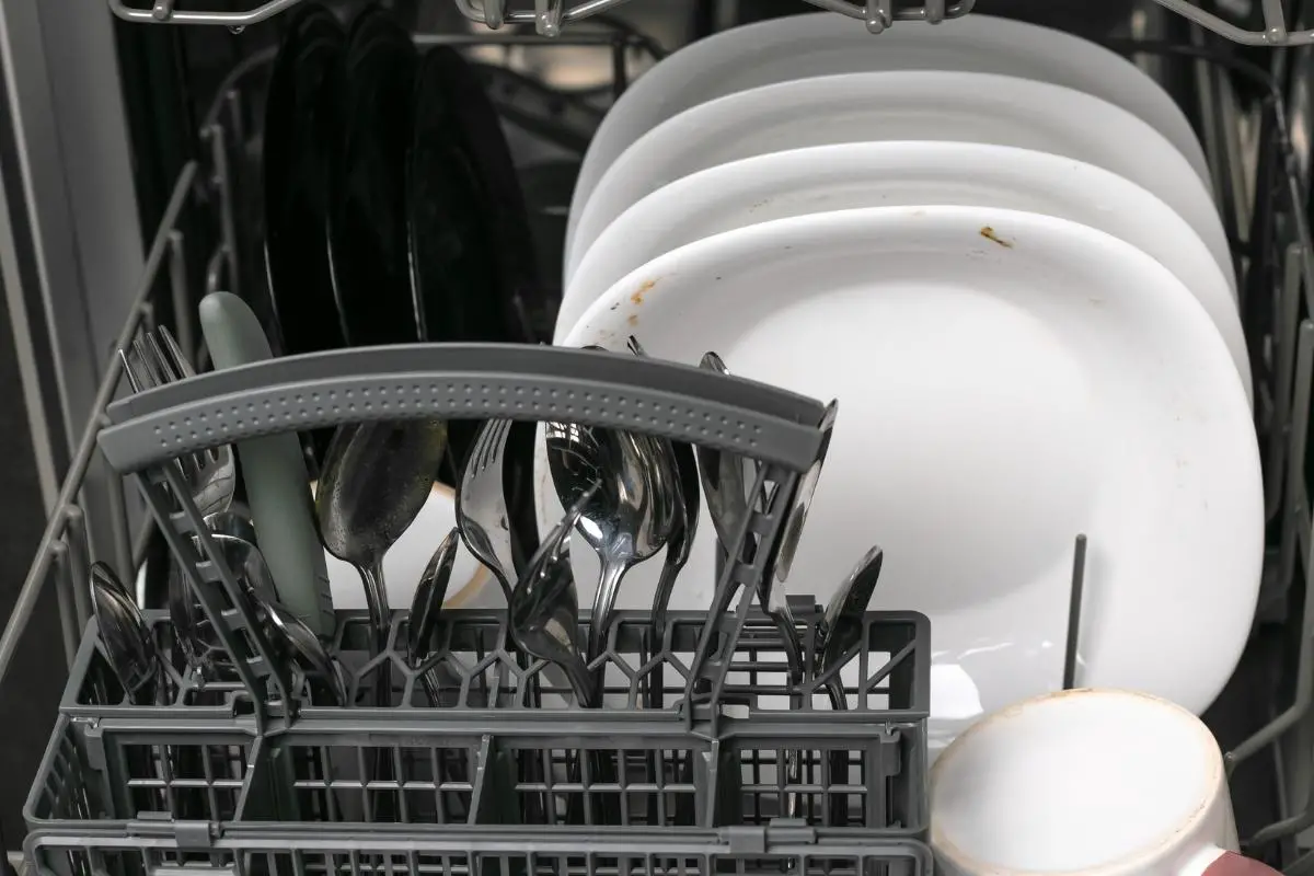 dirty plates, utensils and mugs inside a dishwasher