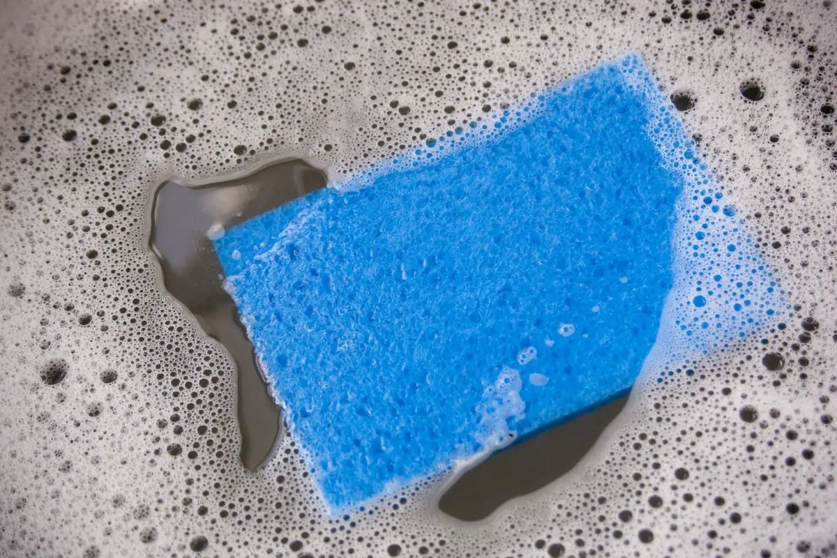 a blue sponge floating in a sink full of soapy water
